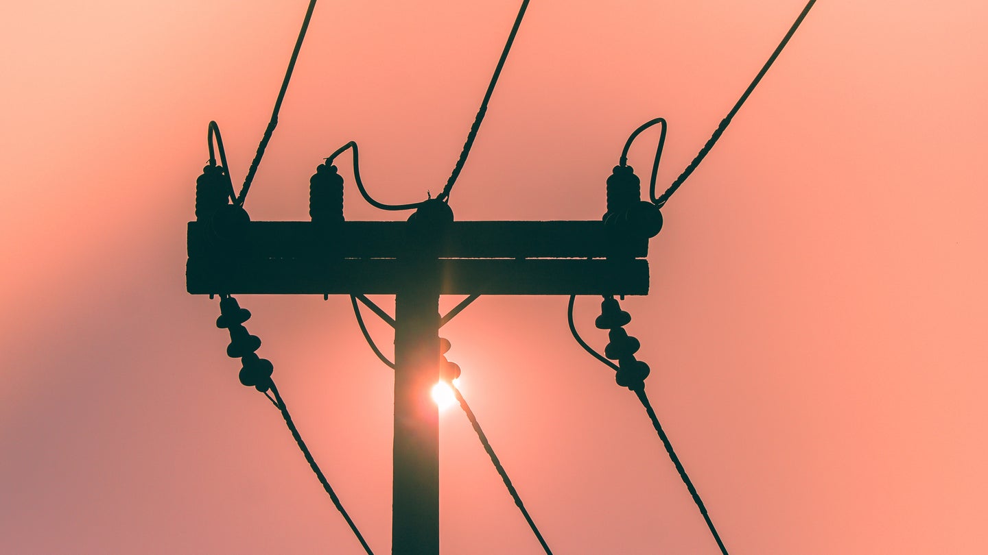Sun setting behind an high voltage power line transformer