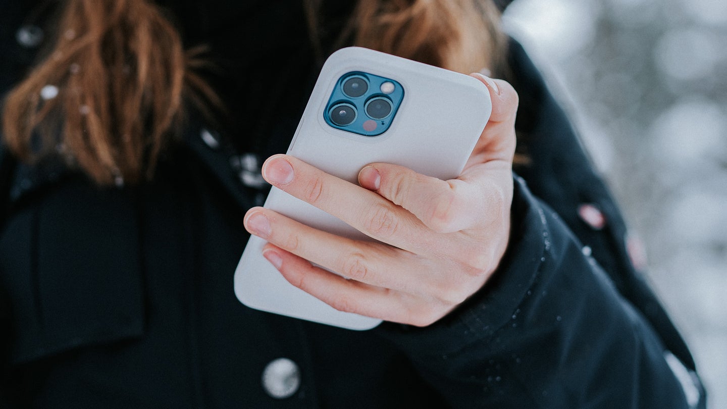Person outdoors holding a white iPhone on their hands.