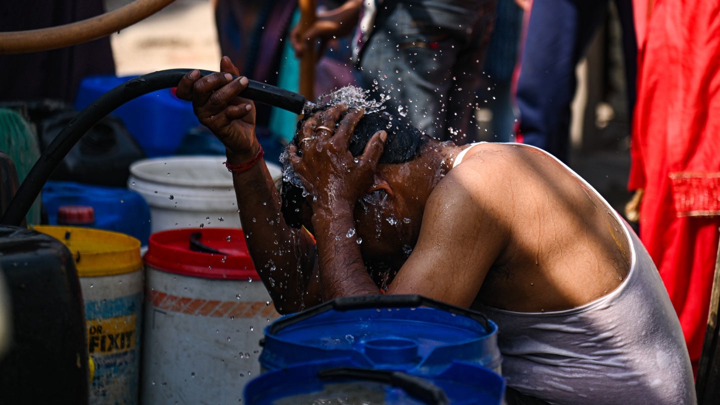 A man dumps water on his head from a Municipal Water Tanker to cool himself outside a slum cluster on a hot summer day in New Delhi, India on May 23, 2023.