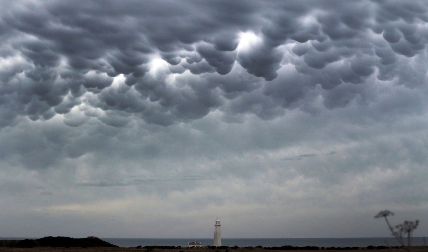 Mammatus types of clouds over a lighthouse and rocky coast