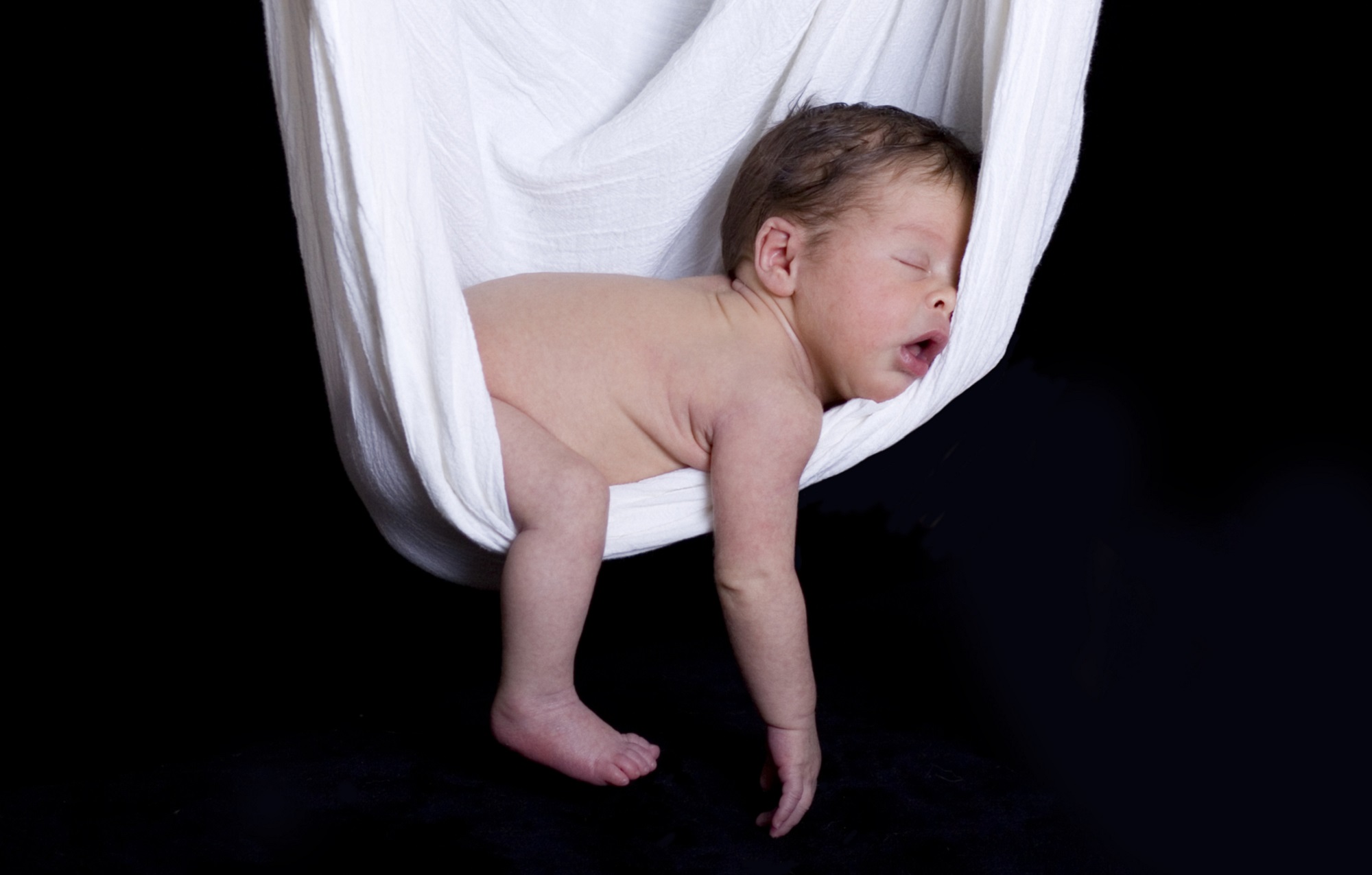 Baby sleeping naked in a white hammock