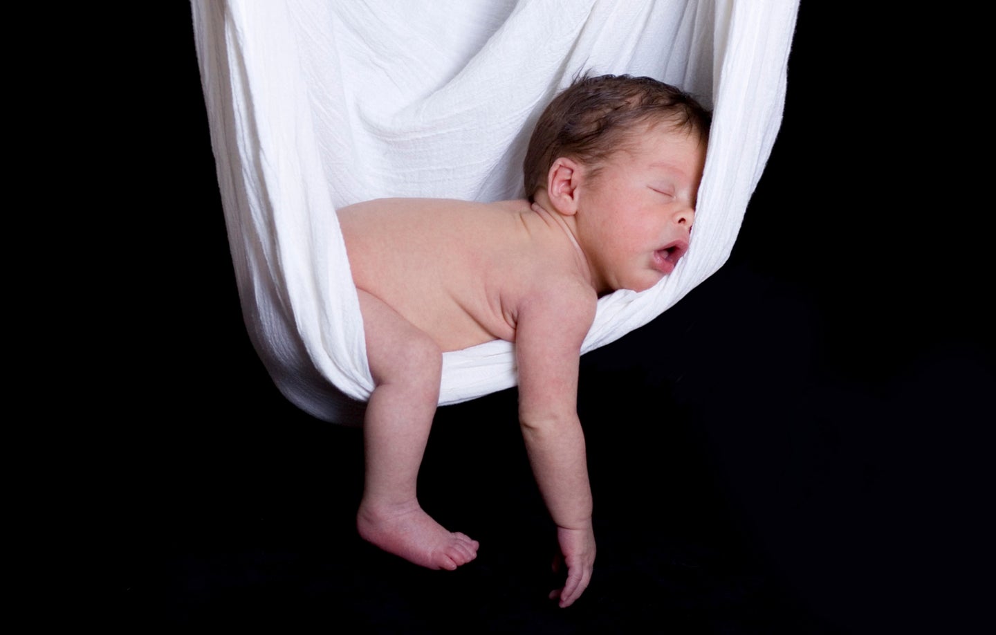 Baby sleeping naked in a white hammock