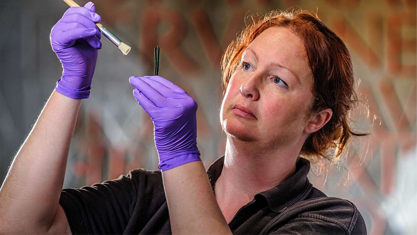 An conservator from English Heritage looks at one of over 50 pairs of tweezers Roman men and women used to remove armpit hair.