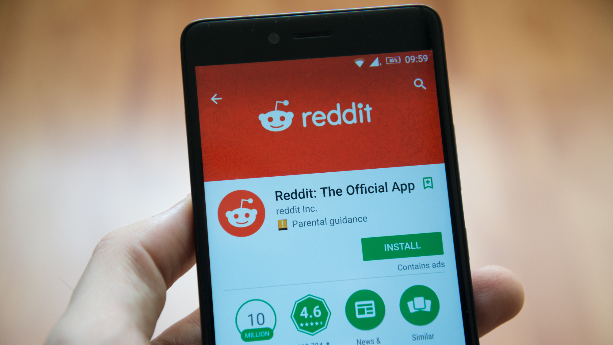 Hand holding smartphone displaying Reddit app download page