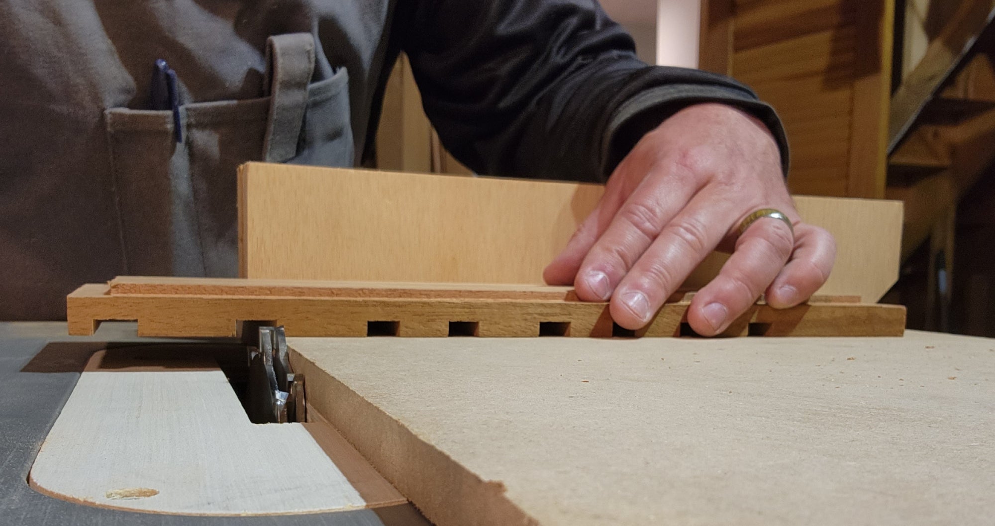 A person cutting dados in a piece of wood for a DIY device charging stand.