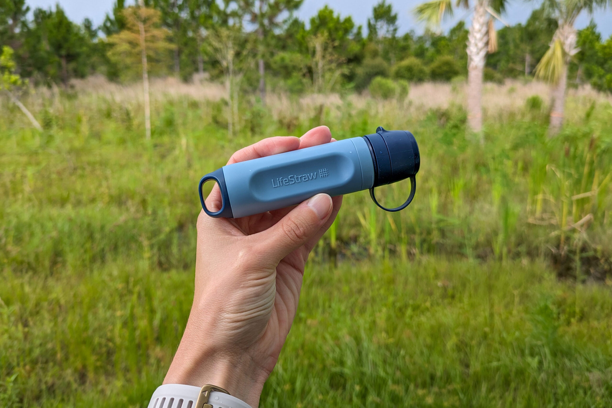 LifeStraw Peak Solo in a hand in front of a forest