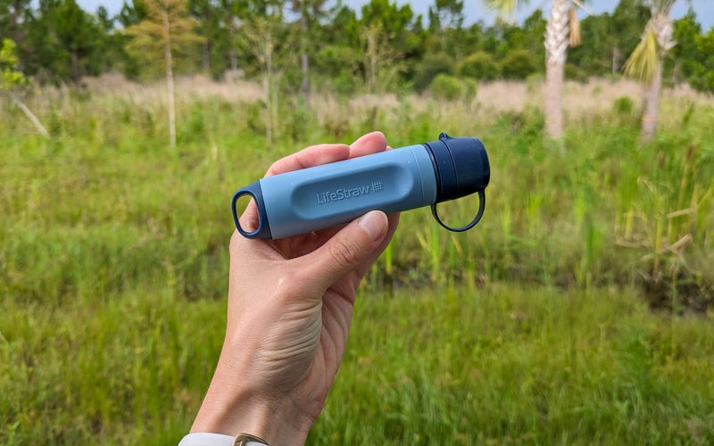 LifeStraw Peak Solo in a hand in front of a forest