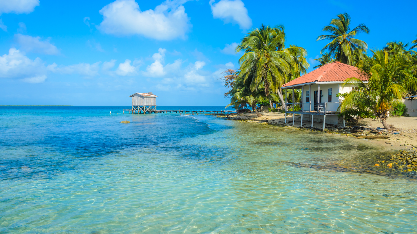 Two small huts near clear, turquoise tropical waters in Tobacco Caye, Belize. he Central American country is the third nation this year to be certified malaria-free.
