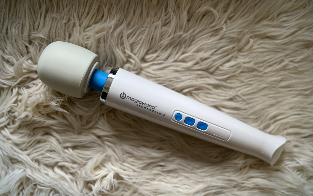 A rechargeable Magic Wand personal massager on a white shag rug