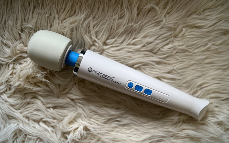 A rechargeable Magic Wand personal massager on a white shag rug