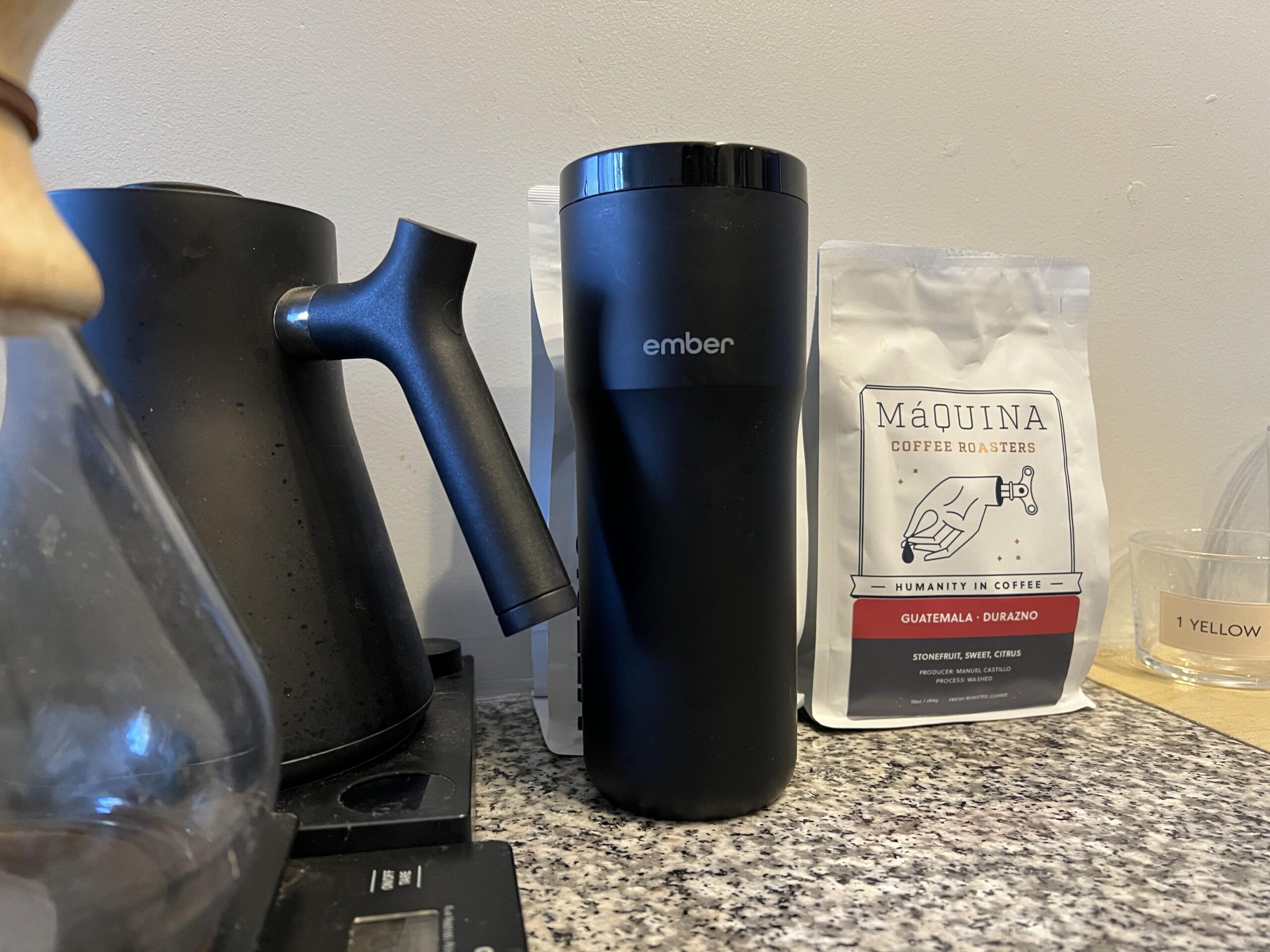 A black Ember smart mug on a marble countertop next to a bag of coffee