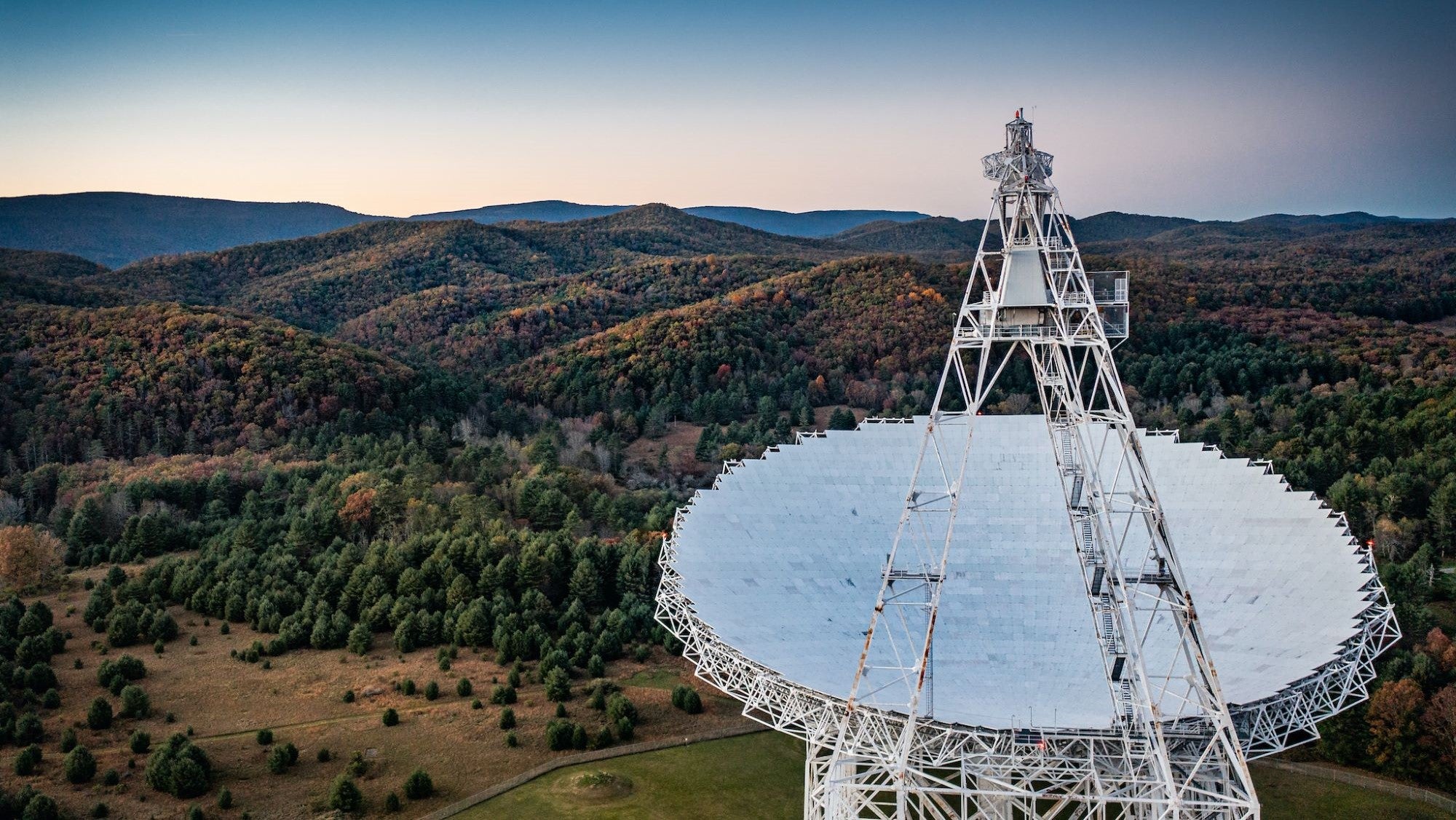 A large telescope array in the foreground with West Virginia hills behind it.