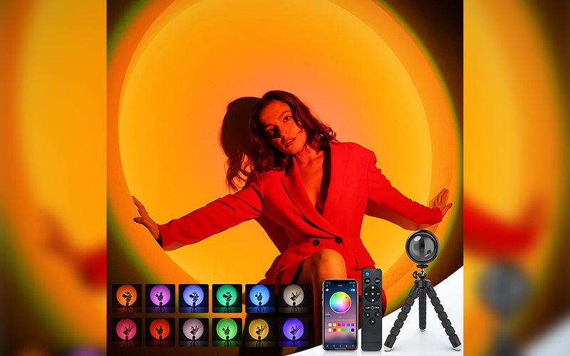 A person posing in front of a white wall, using a nellsi sunset lamp to shine orange light on them