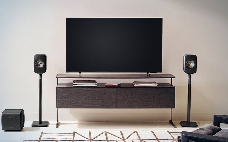 KEF LSX II wireless speakers standmounted next to a flatscreen TV