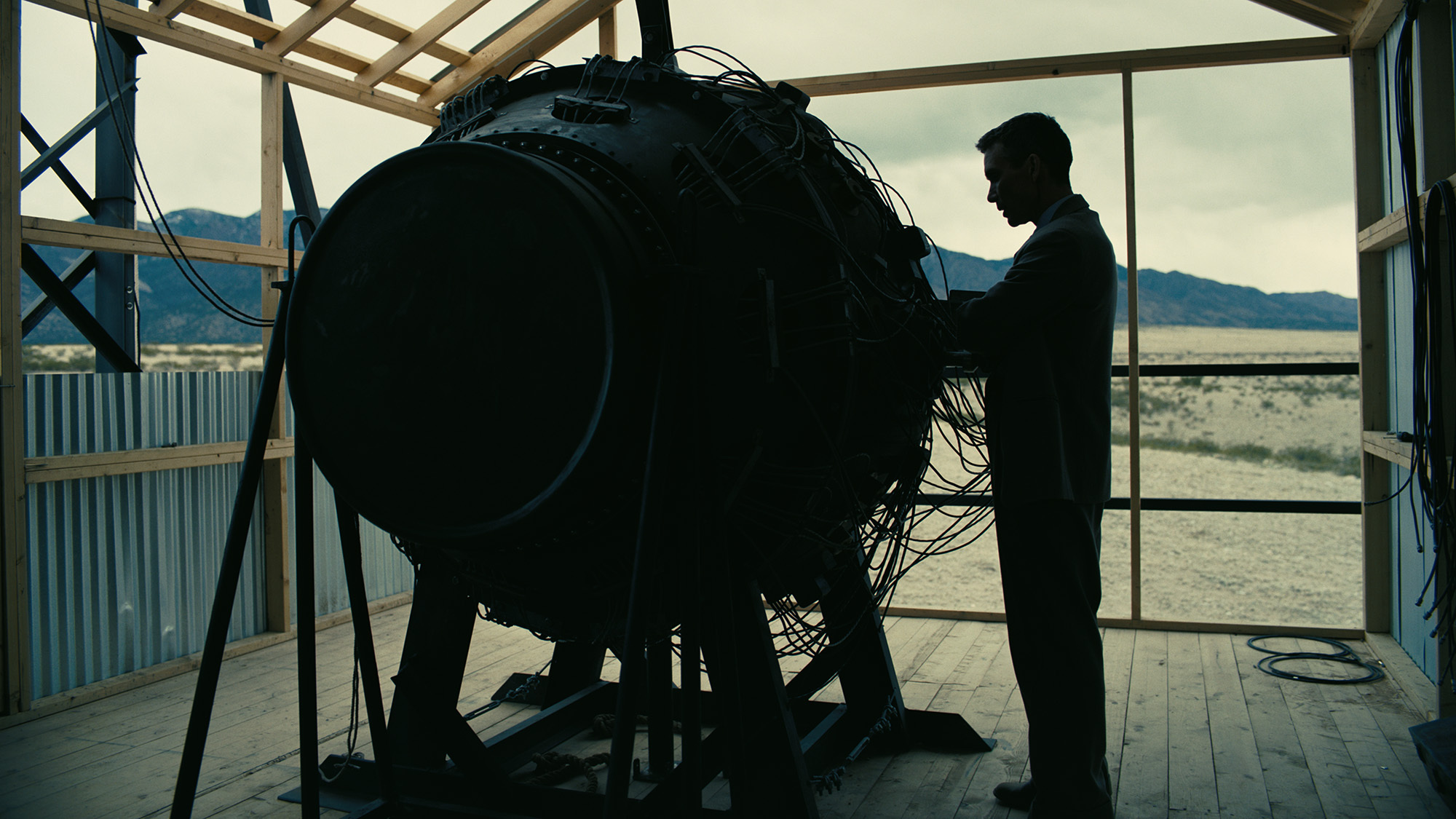 A still from the movie Oppenheimer showing the atomic bomb and Robert Oppenheimer next to one another