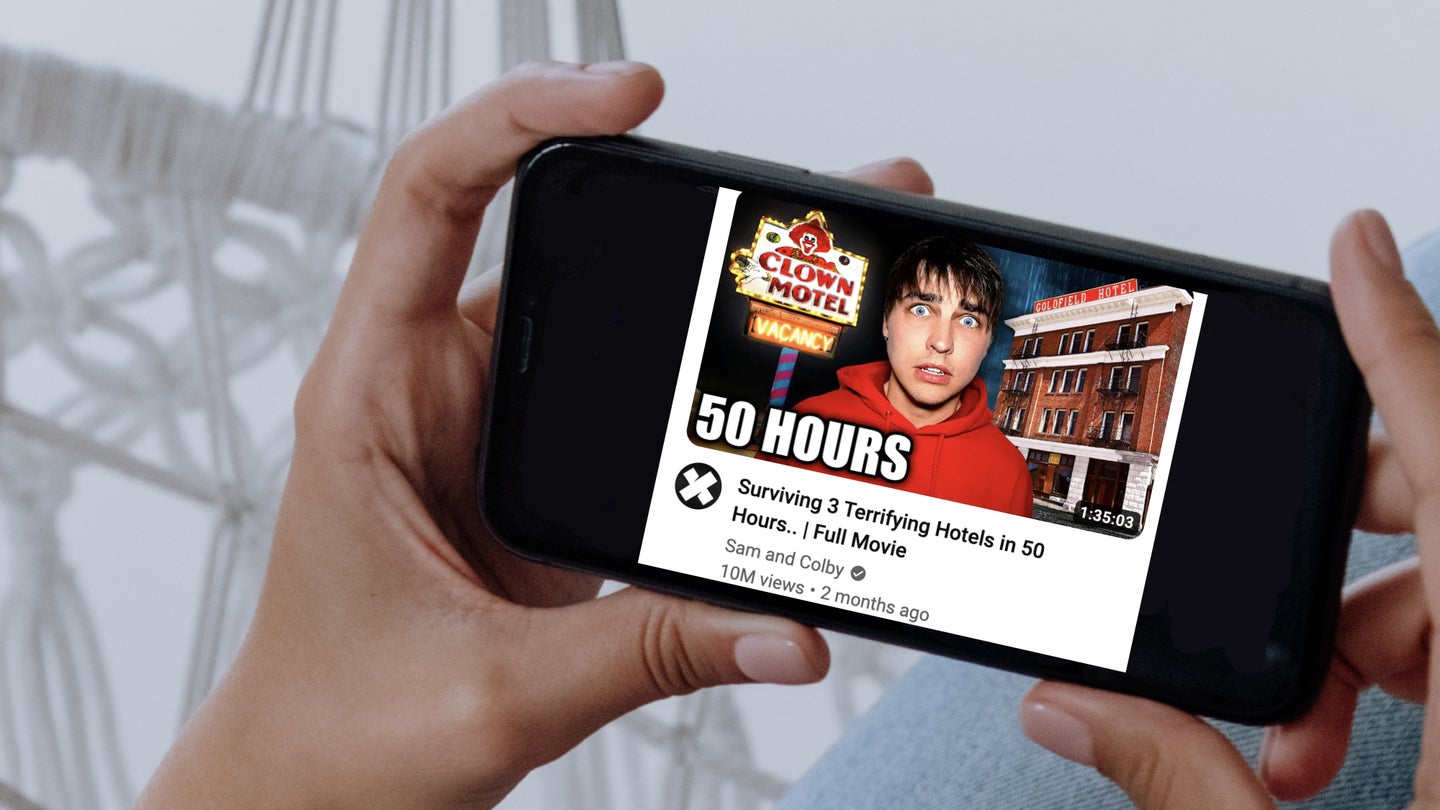 A person holding a phone in landscape view, with a YouTube thumbnail on the screen, showing the exaggerated expression known as YouTube face.