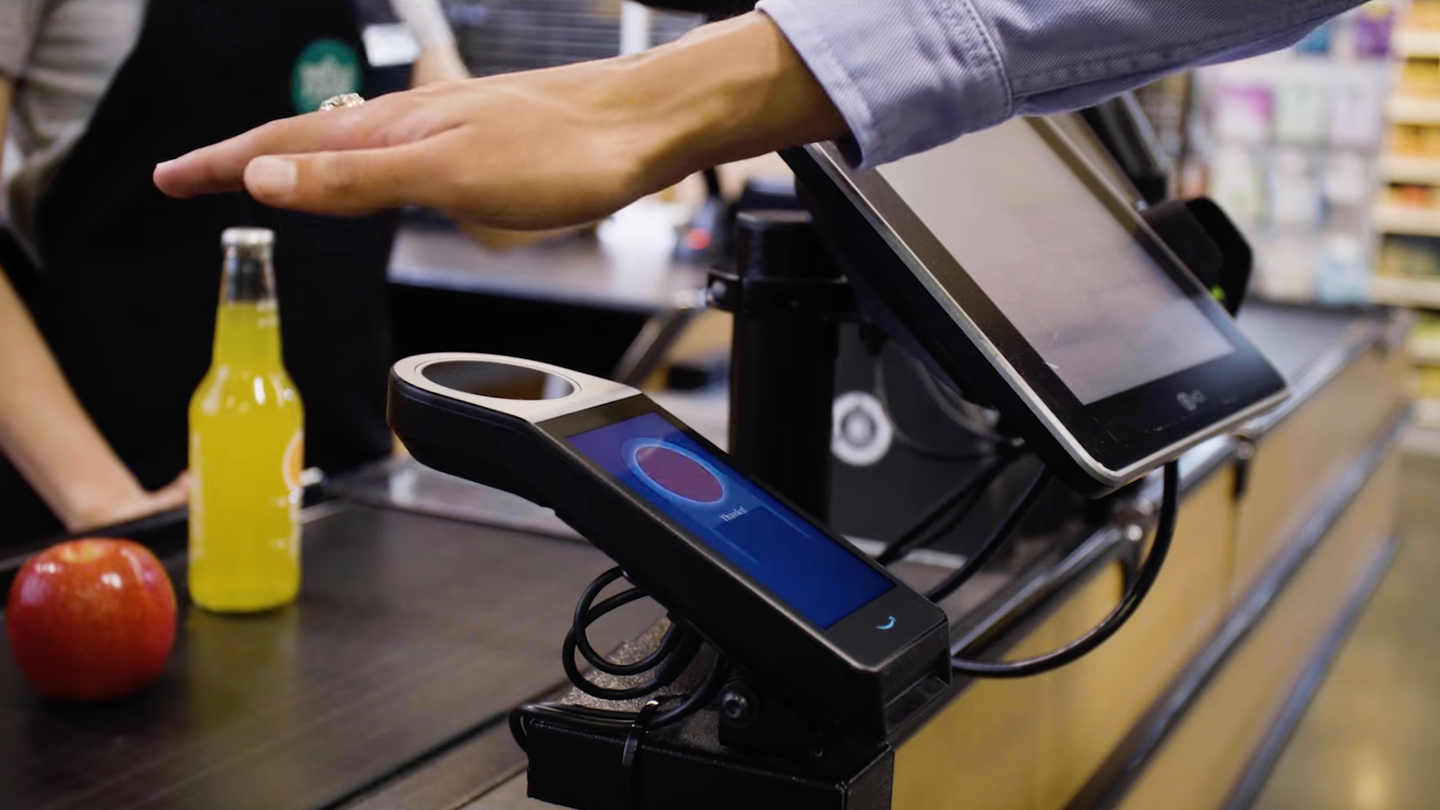 Hand held over Amazon One palm reader payment system at Whole Foods store