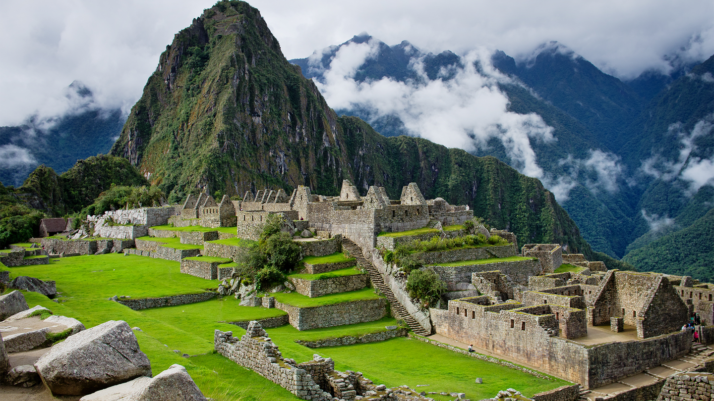A mountain rises above the buildings of Machu Picchu. The former Inca royal estate stands at the meeting point between the Peruvian Andes and the Amazon Basin and is made up of close to 200 structures.