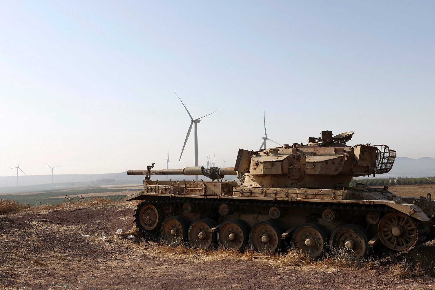 Old Israeli war tank with wind turbines in the background
