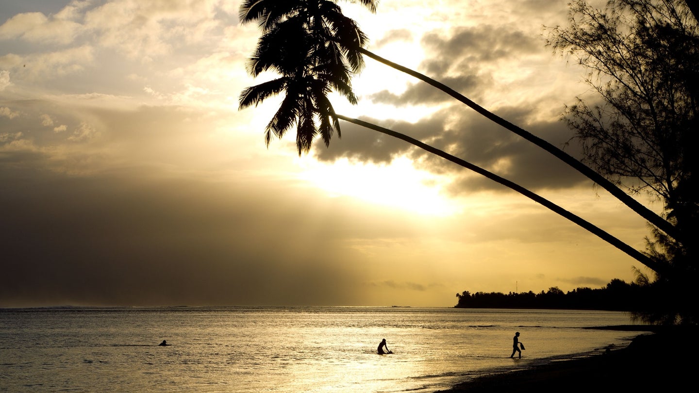 Swimmers walk out of the water after an evening swim on a beach in Avarua on Rarotonga, the largest Island in the Cook Islands.