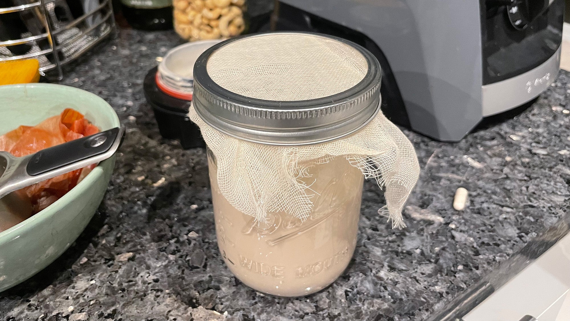 Vegan cream in a mason jar covered with a cheesecloth, one of the steps for making vegan butter.