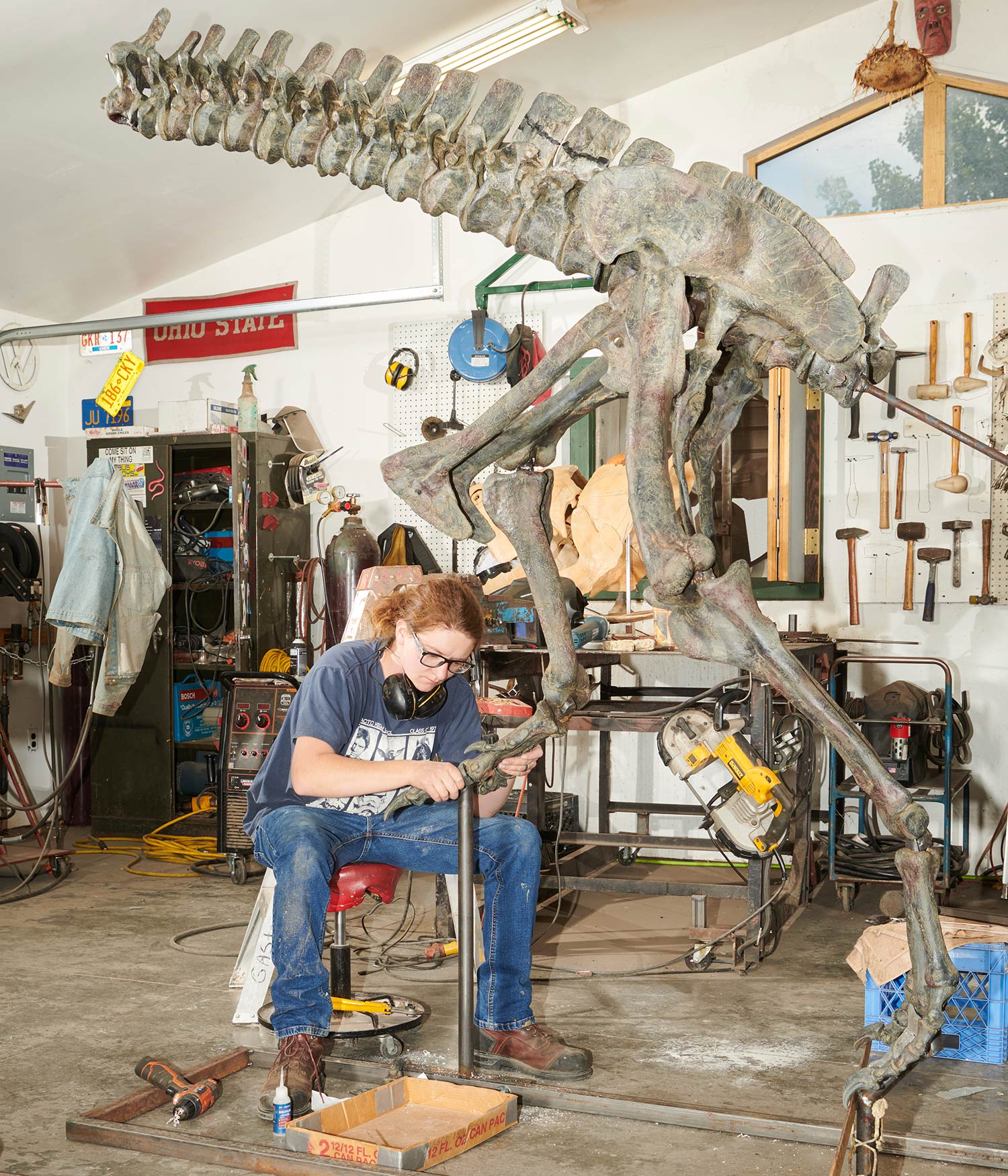 person builds large dinosaur model in workshop