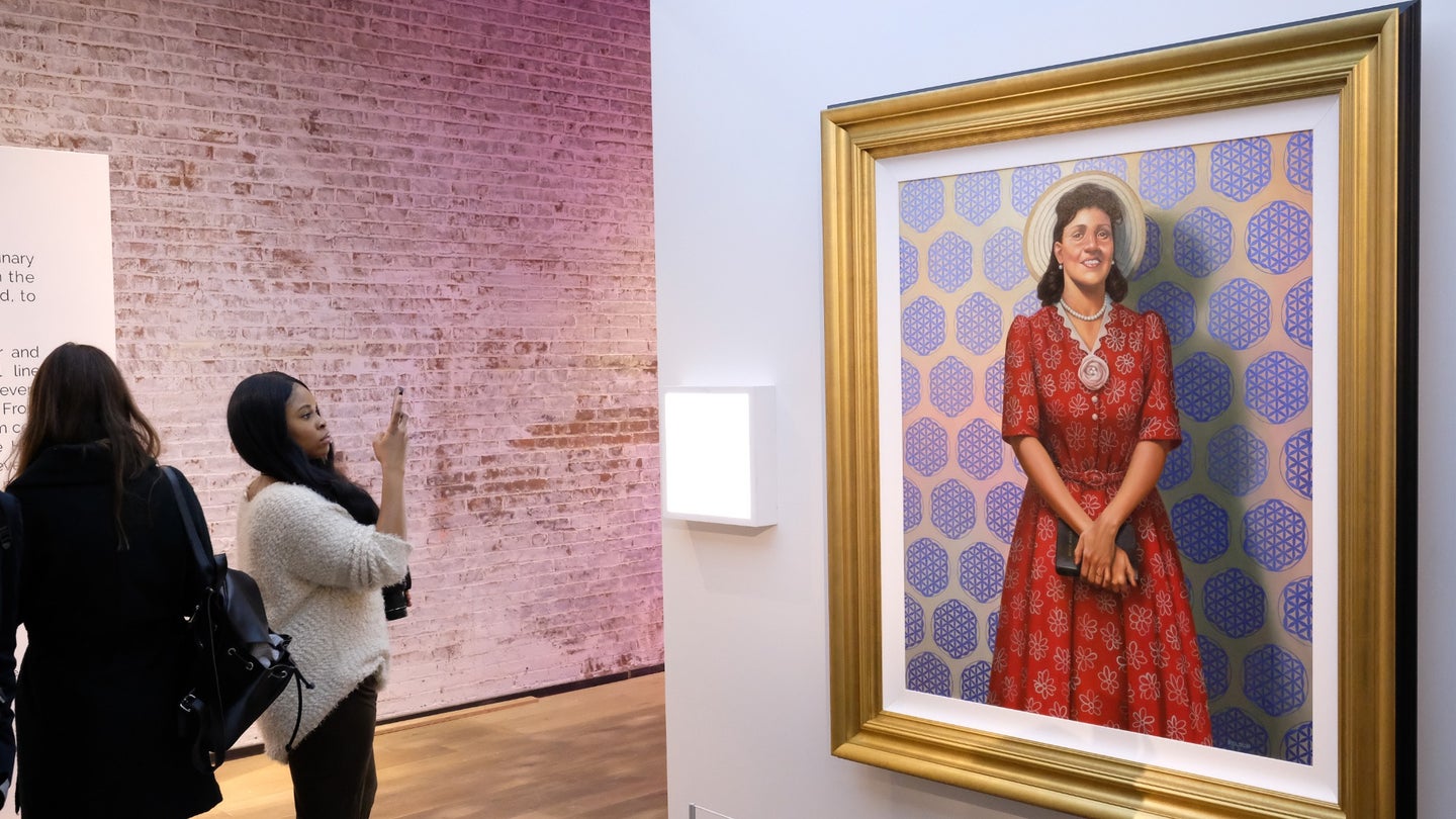 The general atmosphere at HBO's The HeLa Project Exhibit For the film adaptation of "The Immortal Life of Henrietta Lacks" on April 6, 2017 in New York City. Two women stand by a portrait of Lacks wearing a red dress.