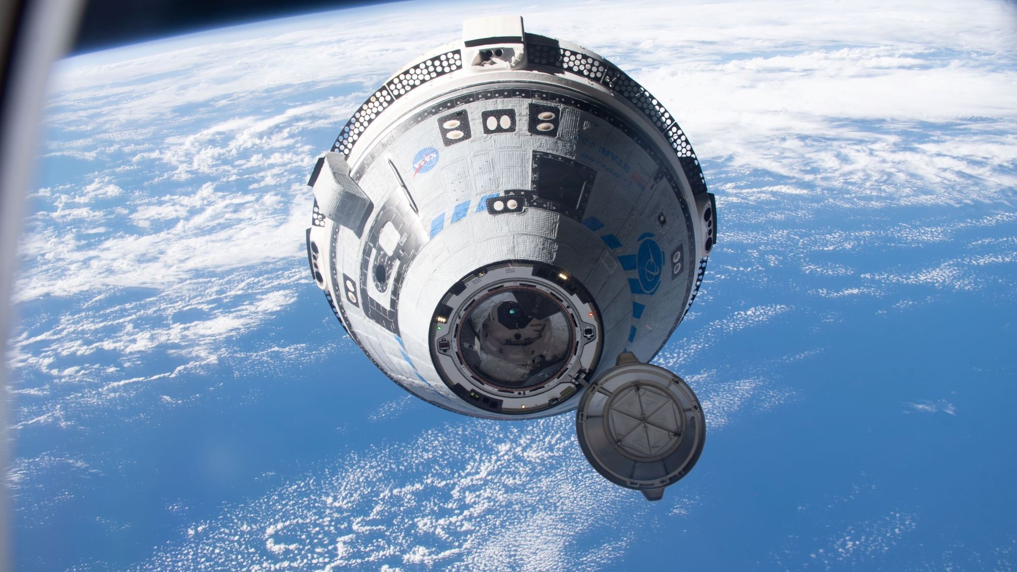 The white Boeing Starliner capsule above a blue Earth.