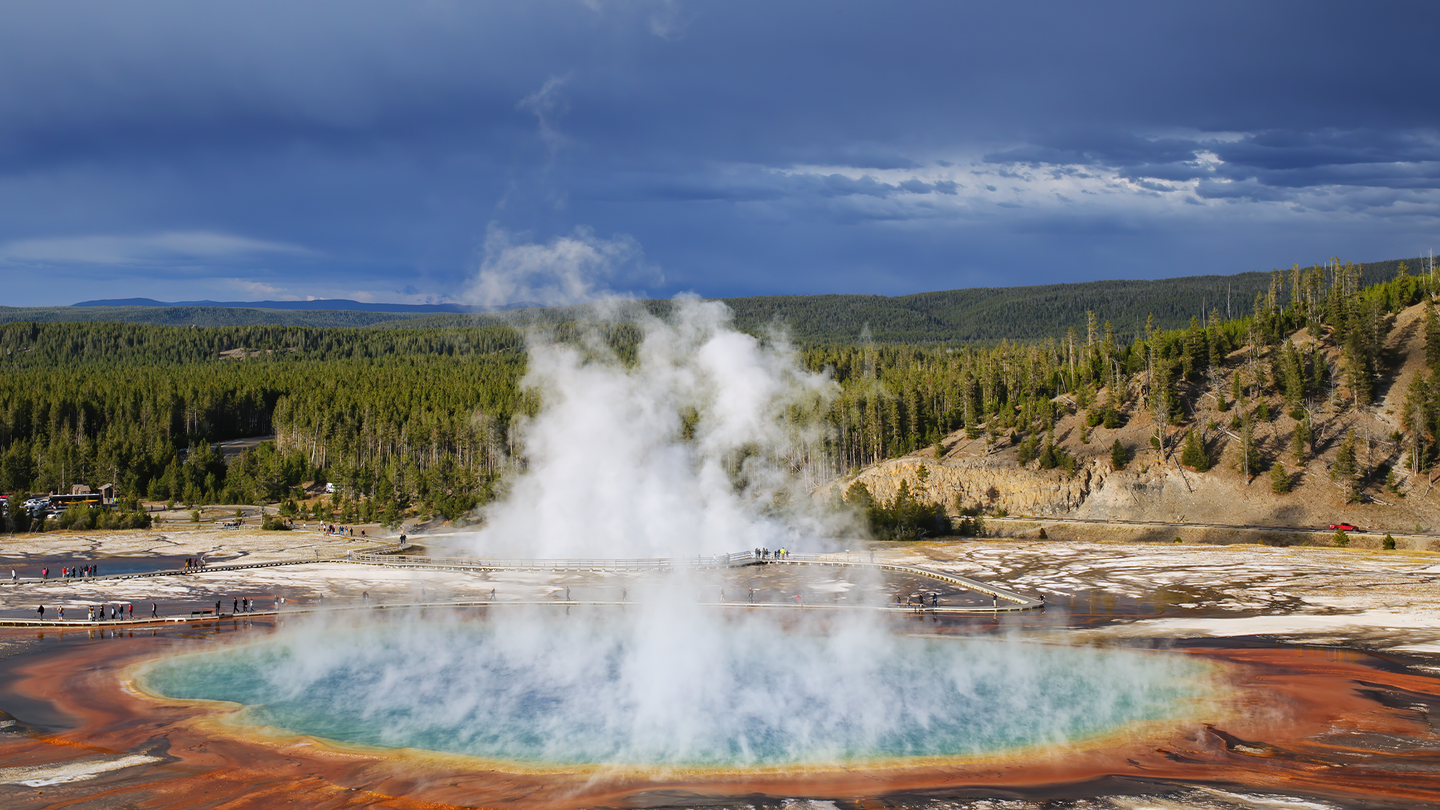 The Grand Prismatic Spring at Yellowstone National Park, with steam rising and mountains in the distance. Temperatures at Yellowstone’s famous hot springs can reach 198 degrees Fahrenheit.