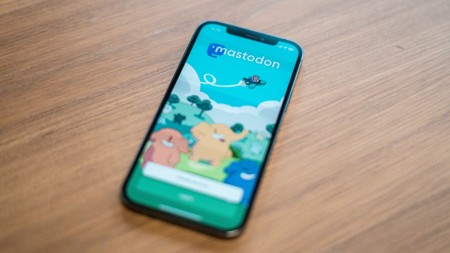 An iPhone on a wooden surface with the sign-in page for Mastodon on the screen.