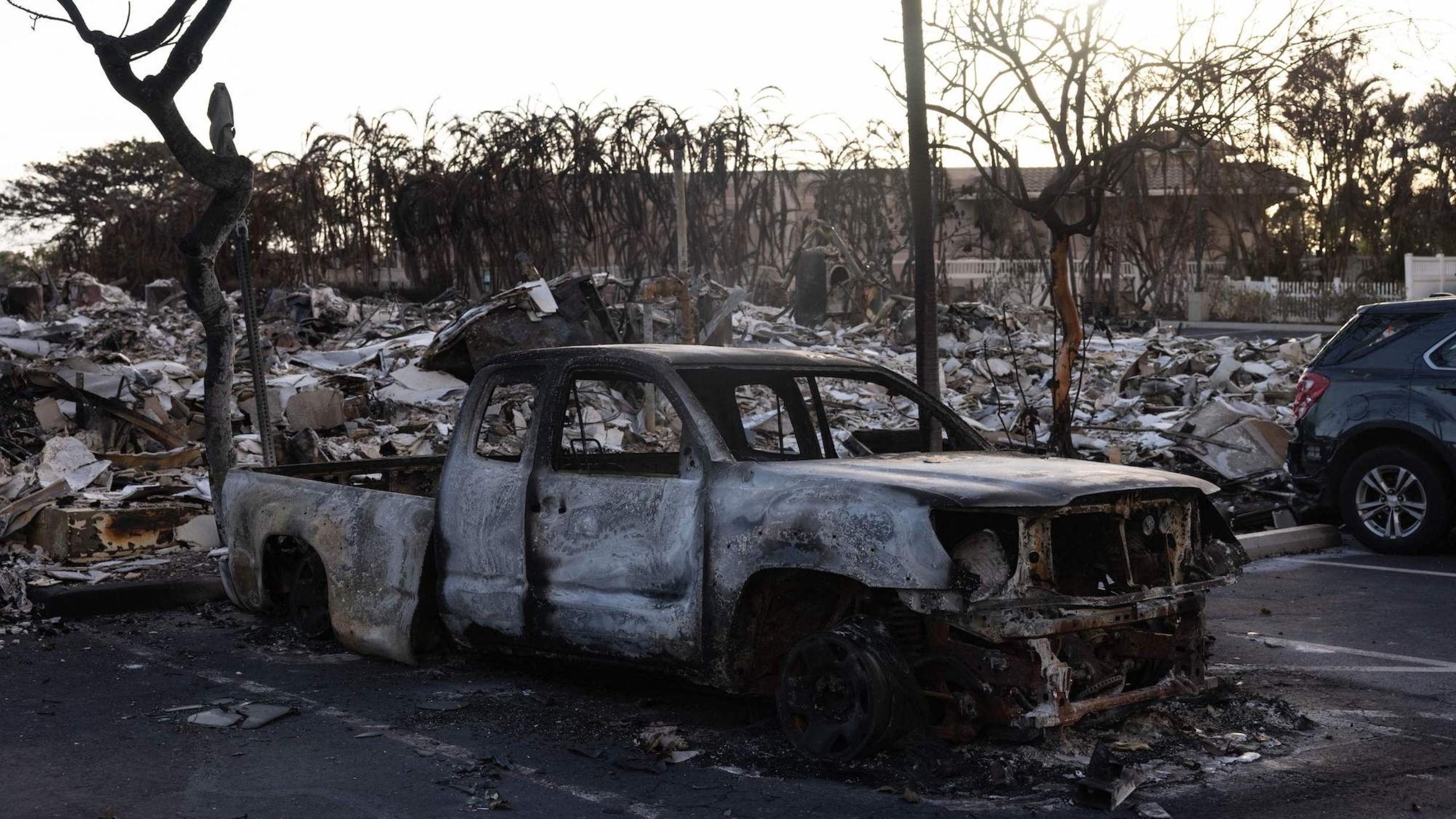 A burnt out car lies in the driveway of charred apartment complex in the aftermath of a wildfire in Lahaina, western Maui, Hawaii on August 12, 2023.