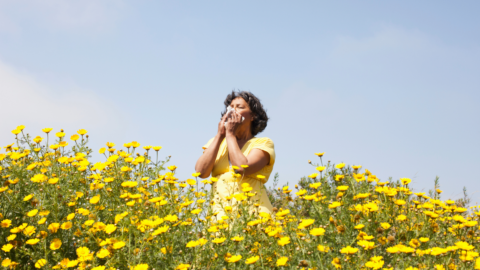 woman smelling flowers in field.