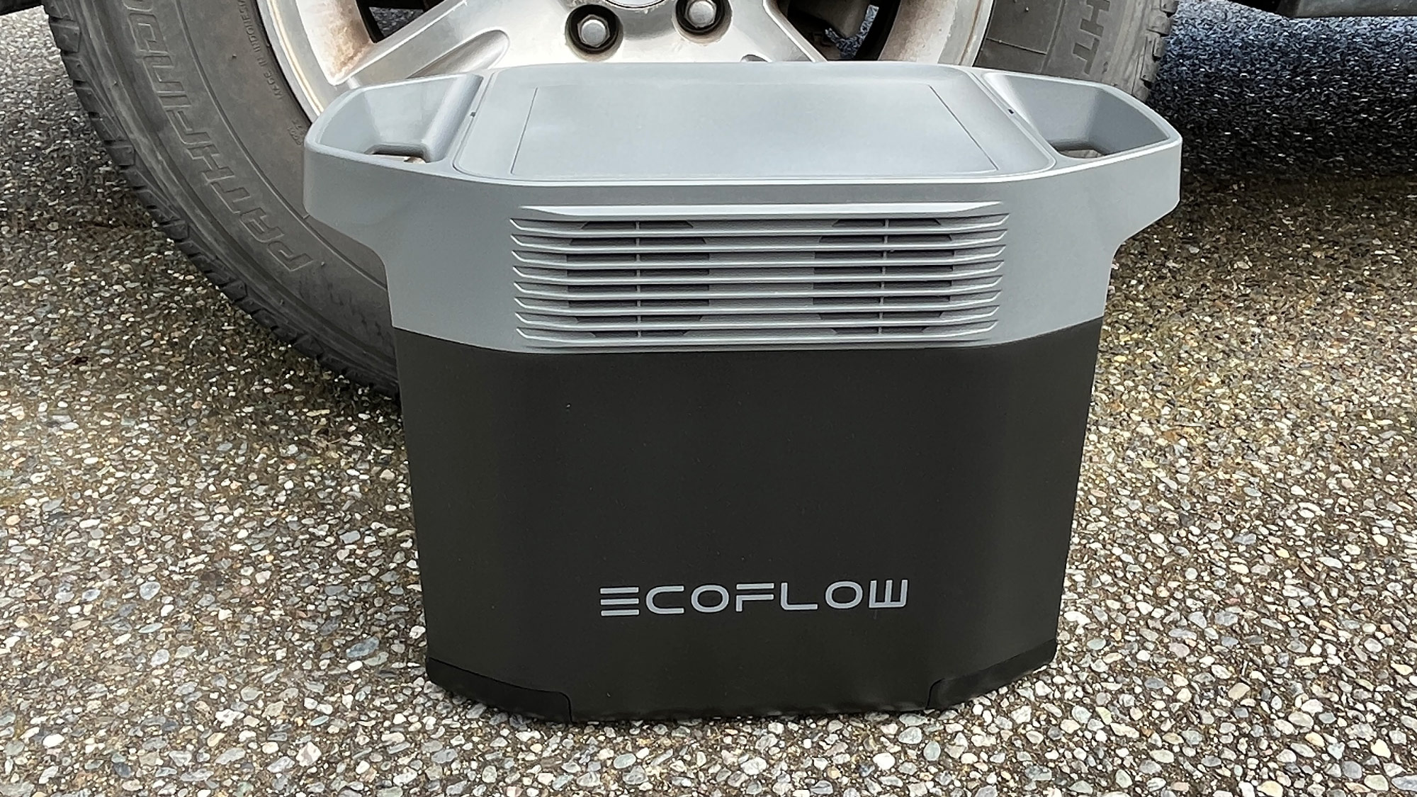 EcoFlow Delta 2 generator sitting on the ground near a truck tire