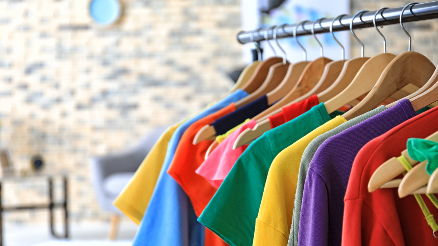 Colorful t-shirts hang on a clothing rack. According to Northwestern University’s Body and Media Lab, women’s clothing tends to be more painful, restrictive, and distracting, which can interrupt focus and make it more difficult to move around in the workplace.