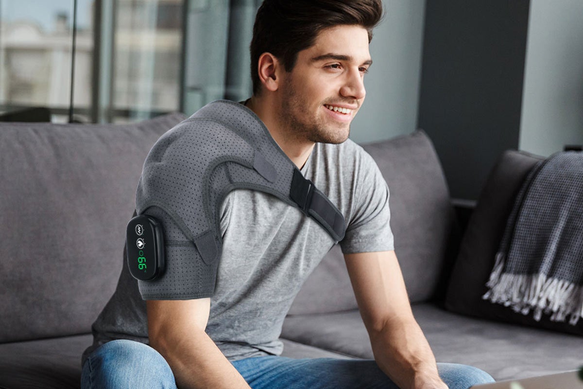 A person wearing a massage belt on their shoulder.