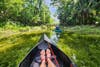 Legs in a kayak going through a narrow canal through a forest.