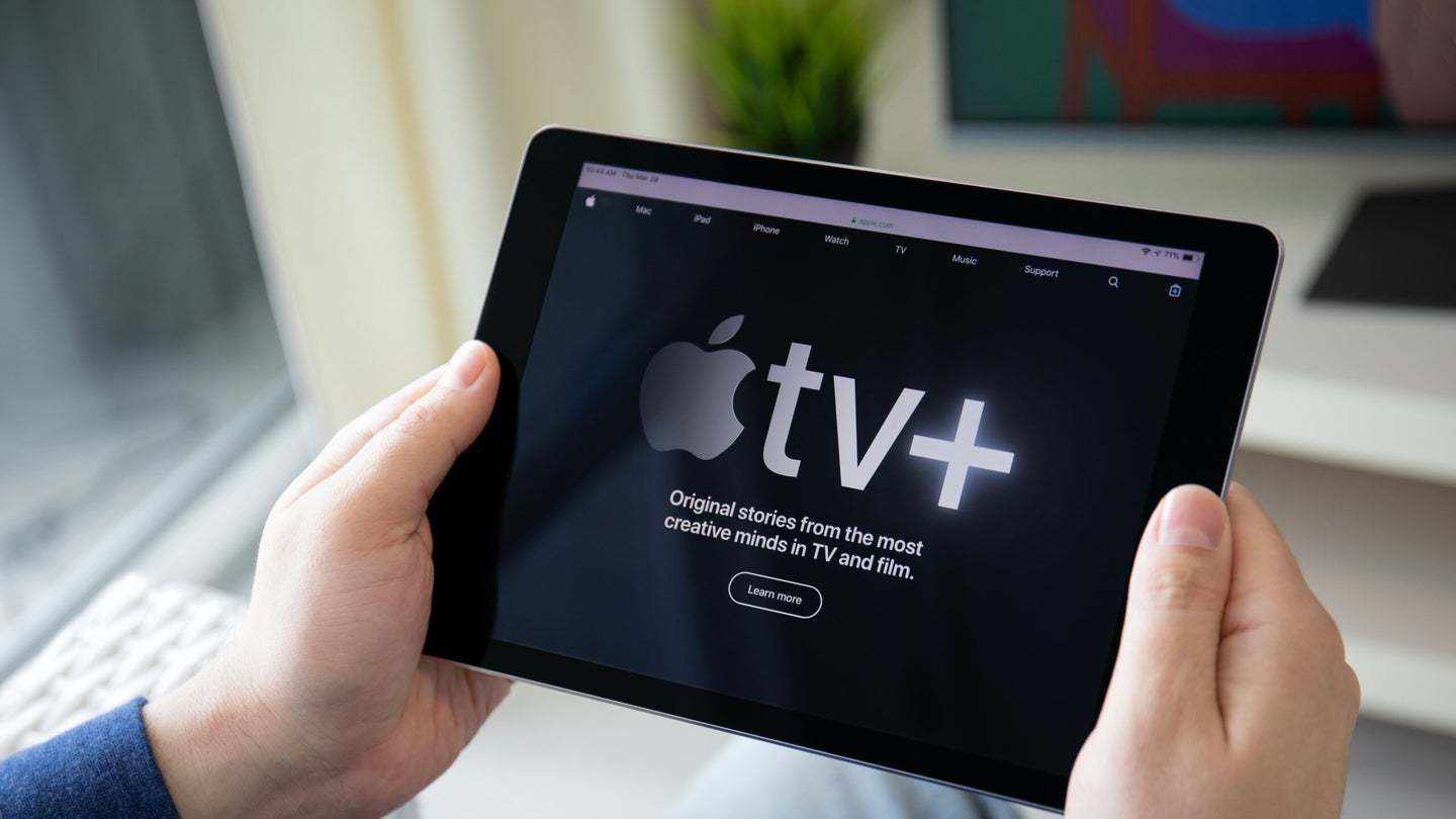 A person holding an iPad with Apple TV+ on the screen.