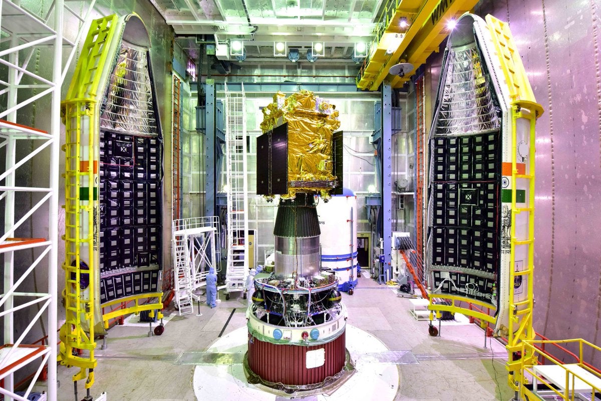 A spacecraft wrapped in gold foil in a clean room.