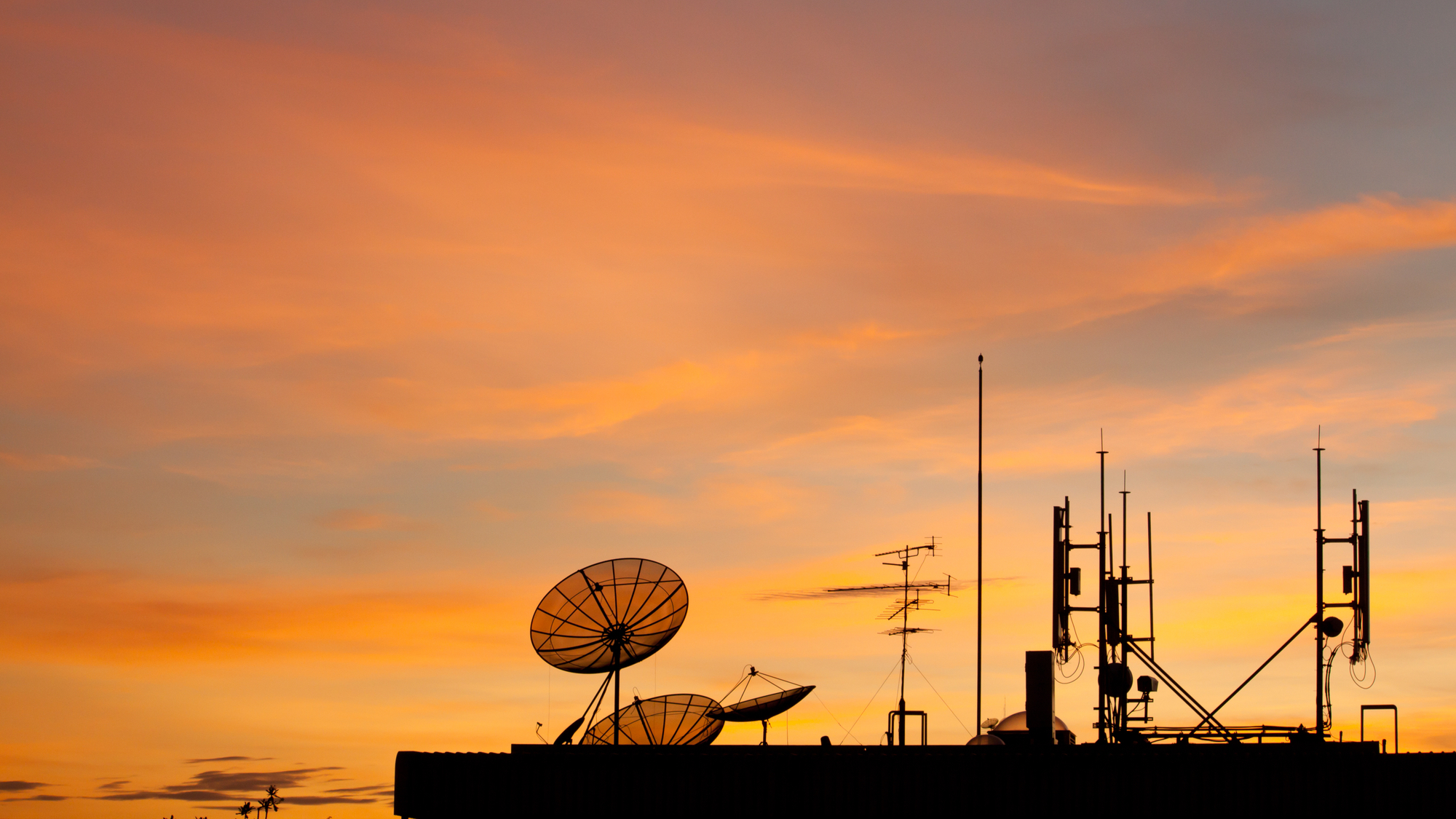 Worldwide Communication, Satellite and other antenna network against sky at sunset, silhouette style