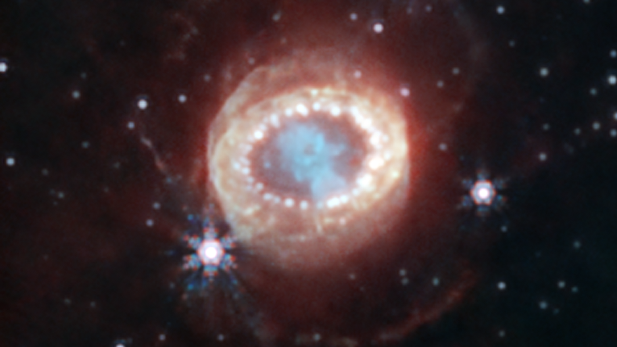 Webb’s NIRCam (Near-Infrared Camera) captured this detailed image of SN 1987A (Supernova 1987A). At the center, material ejected from the supernova forms a keyhole shape.
