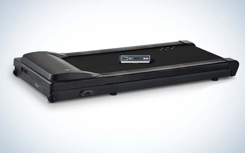 A black, compact walking treadmill with a remote control on top.
