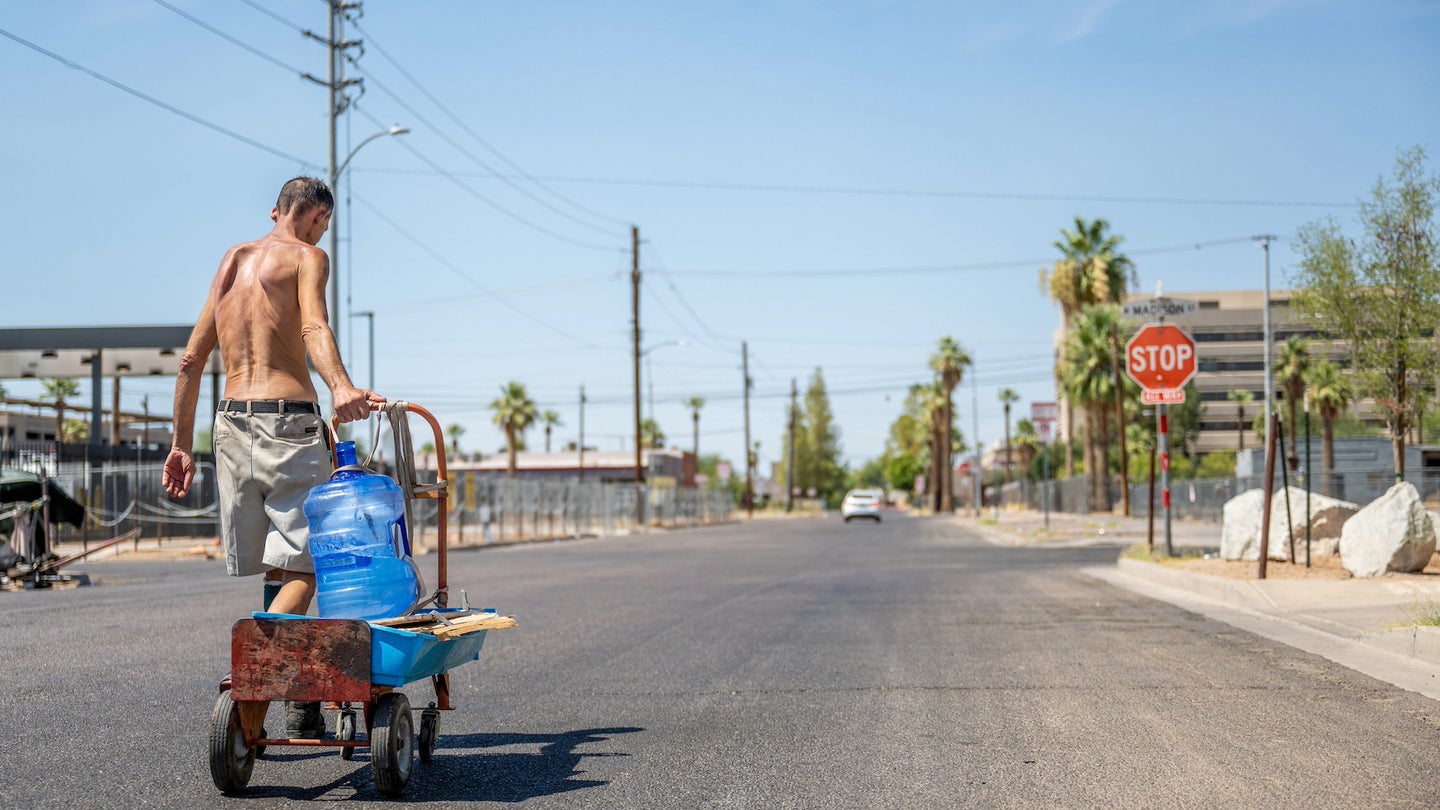 A person transports water jugs through a neighborhood on July 14, 2023 in Phoenix, Arizona. July 14 marked the Phoenix area's 15th consecutive day of temperatures exceeding 110 degrees.