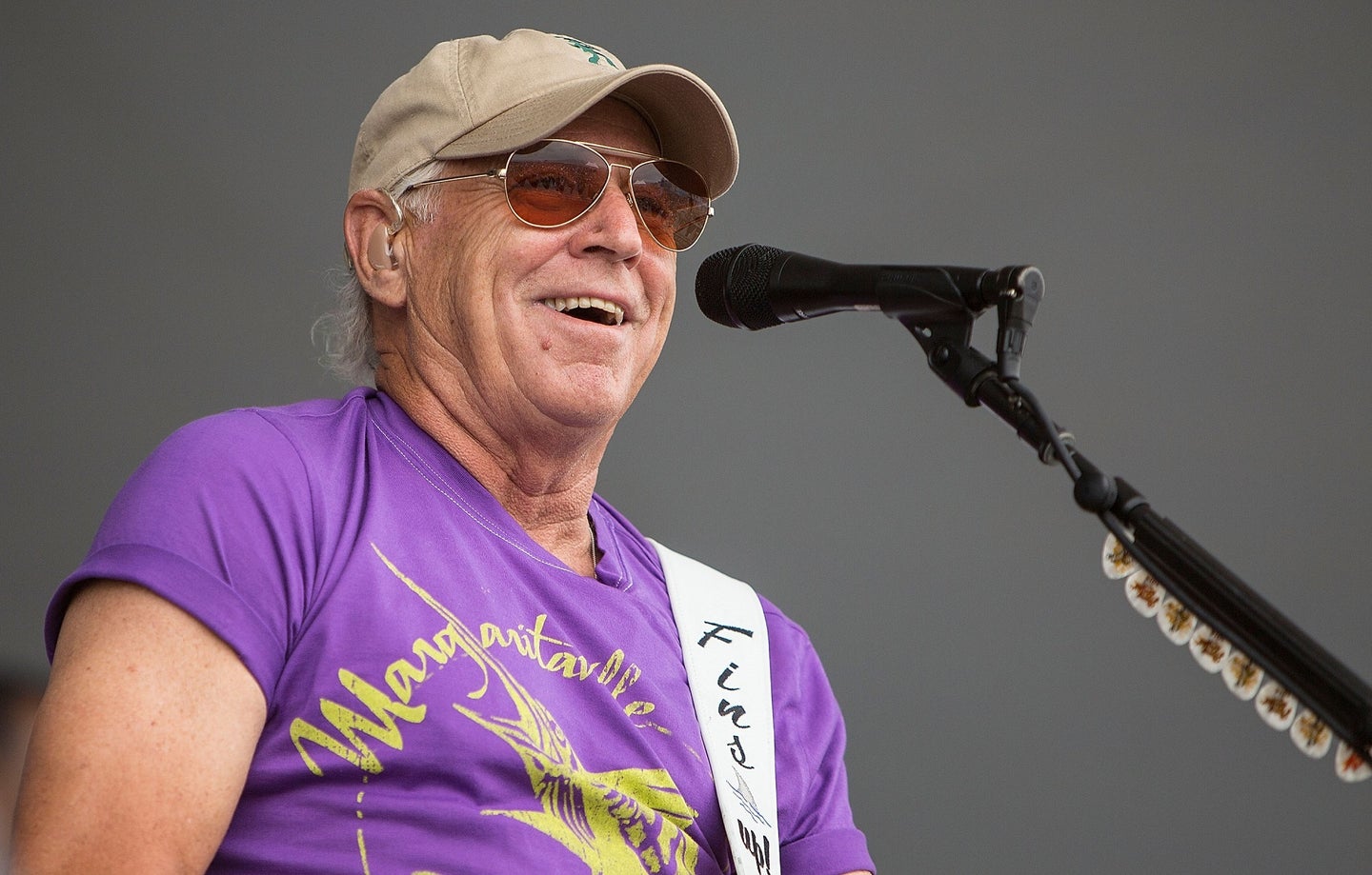 Singer Jimmy Buffet in a purple shirt by a microphone.