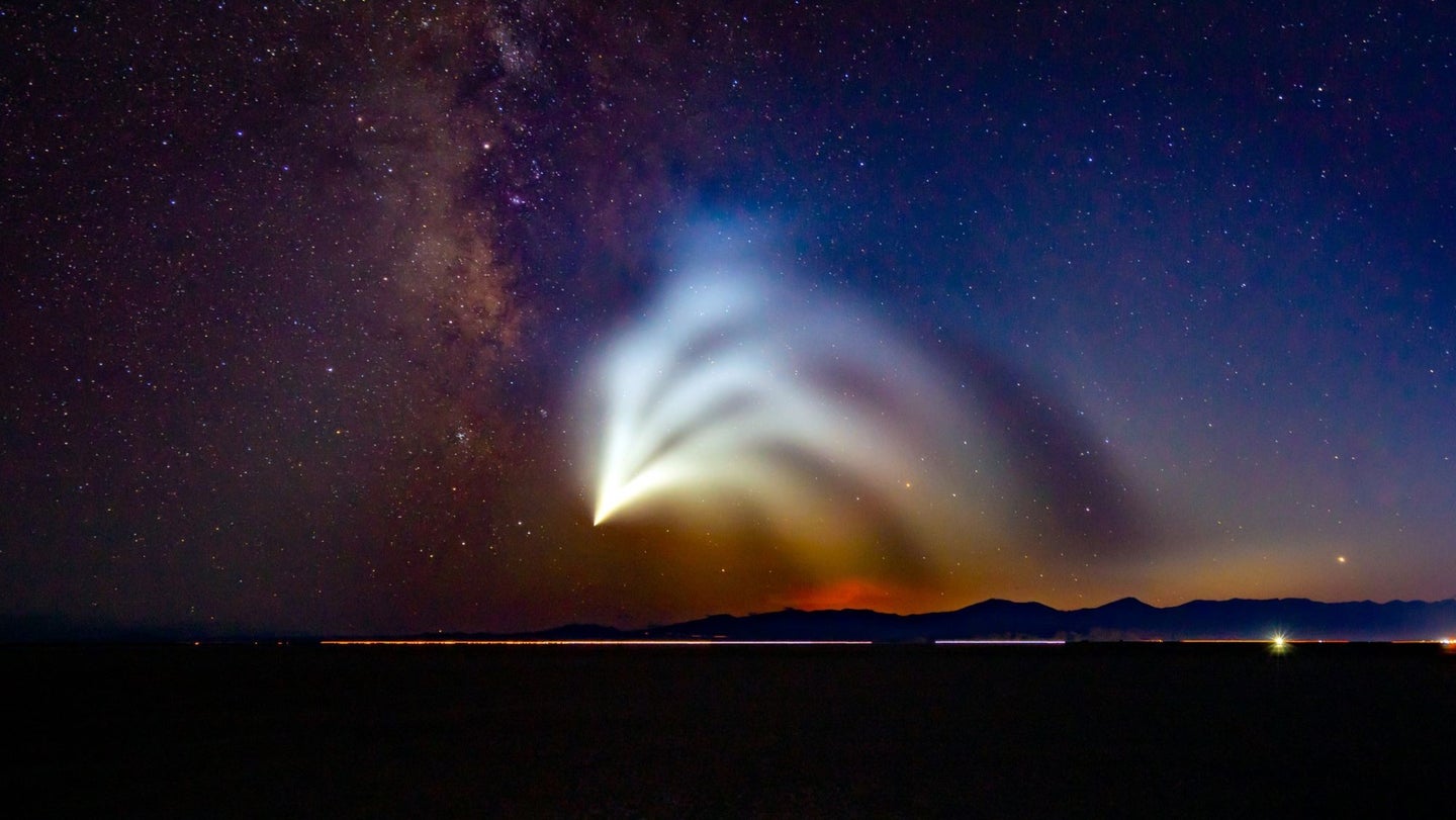 A rocket launch creates strange contrails in front of the Milky Way.
