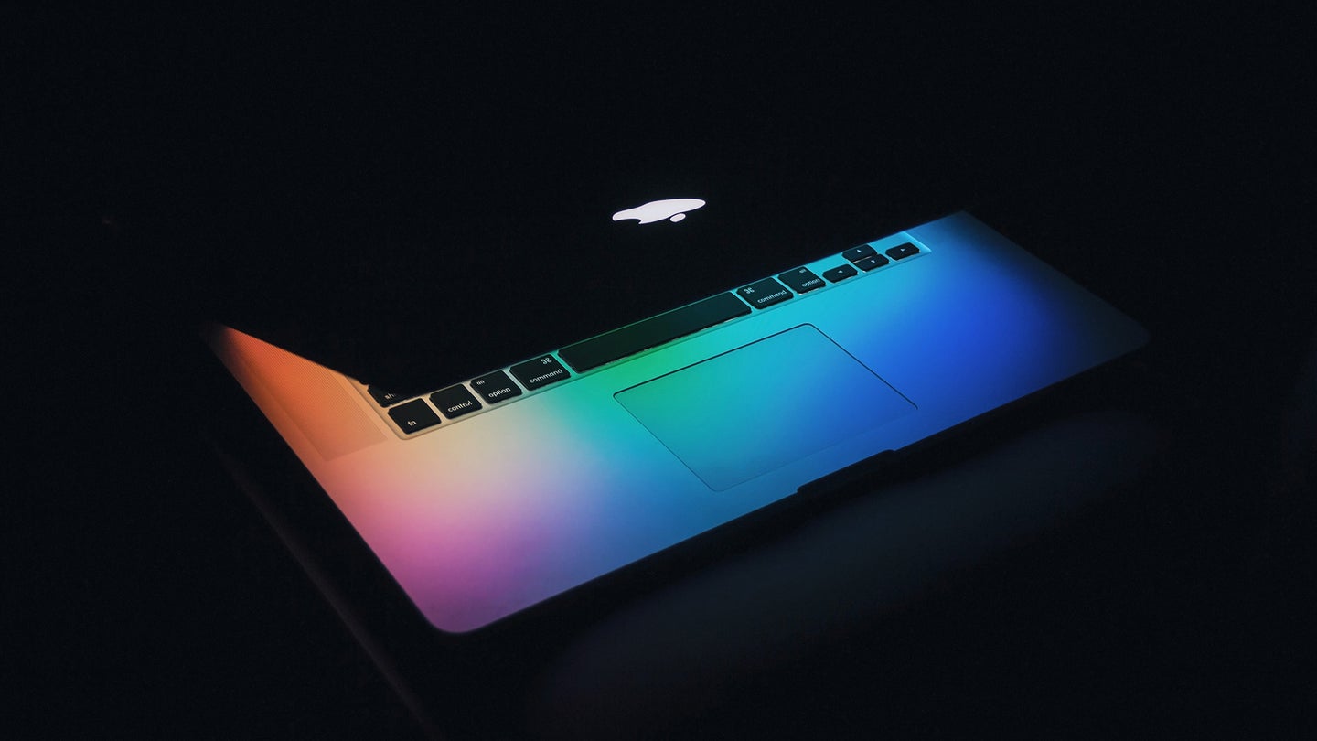 A Macbook sits semi open in the dark