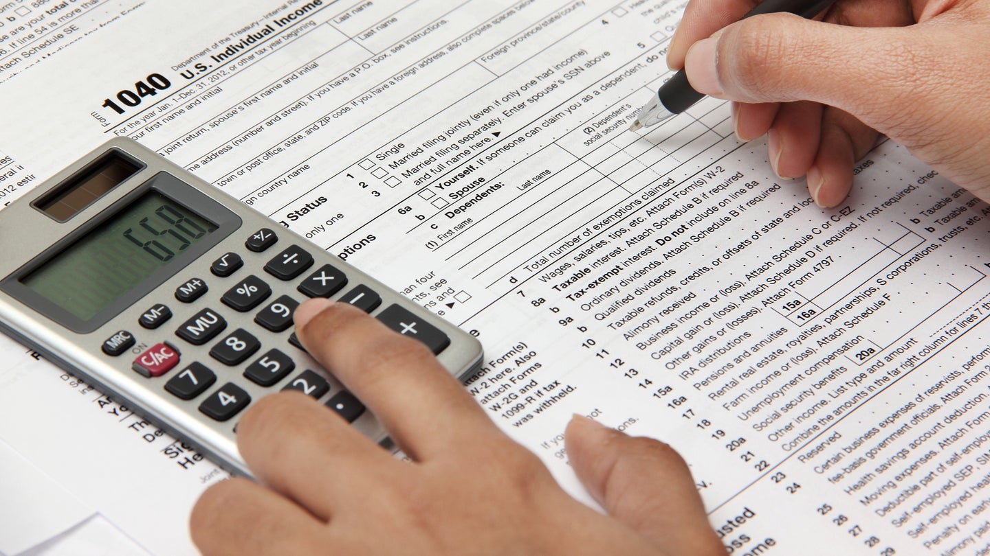 Person completing 1040 tax form with calculator