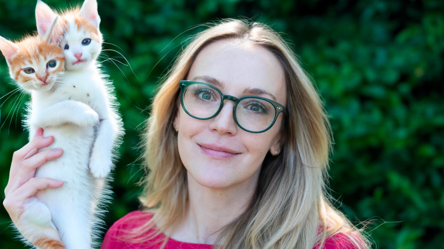 Annie Colbert holds up two-headed kitten, photo altered using AI