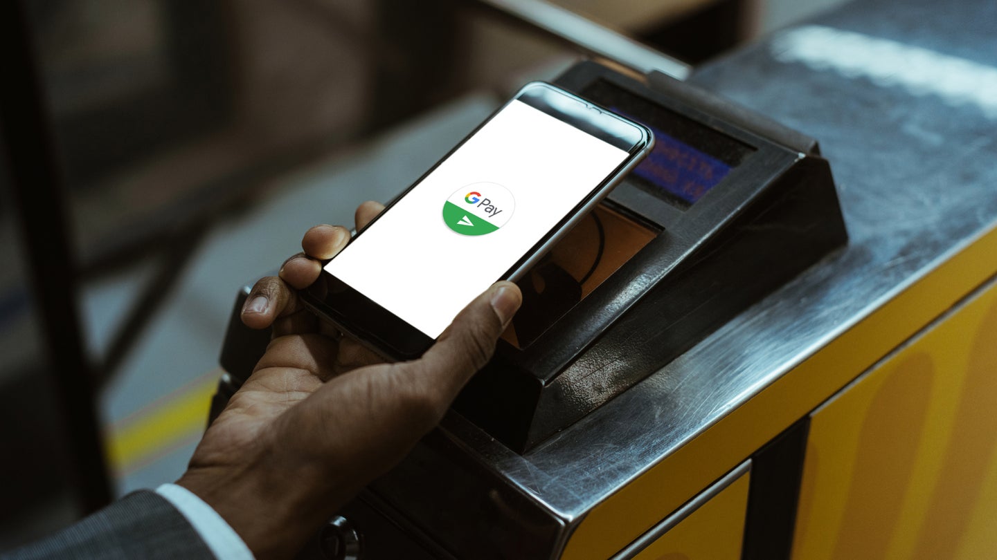 A person holding an iPhone over a scanner so they can use Google Pay to make a purchase.