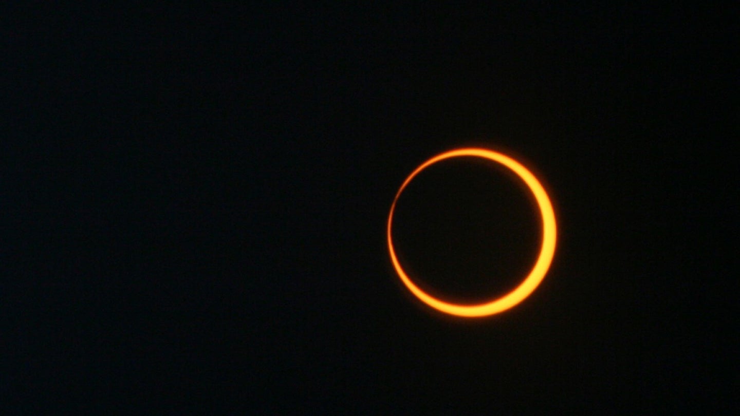An annular eclipse, with an orange solar ring around a black moon.