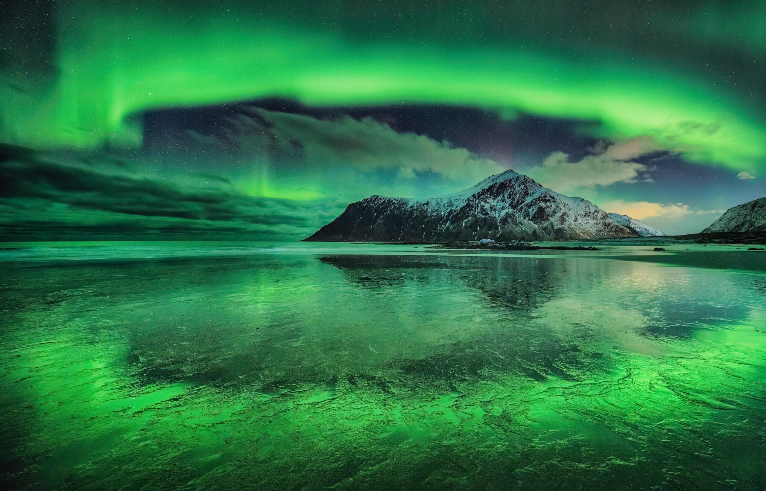 Green aurora encircling a mountain and lake